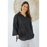Women wearing black lilly shirt with a decorative background behind - front 