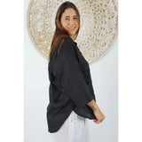 Women wearing black lilly shirt with a decorative background behind - side