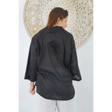 Women wearing black lilly shirt with a decorative background behind - back